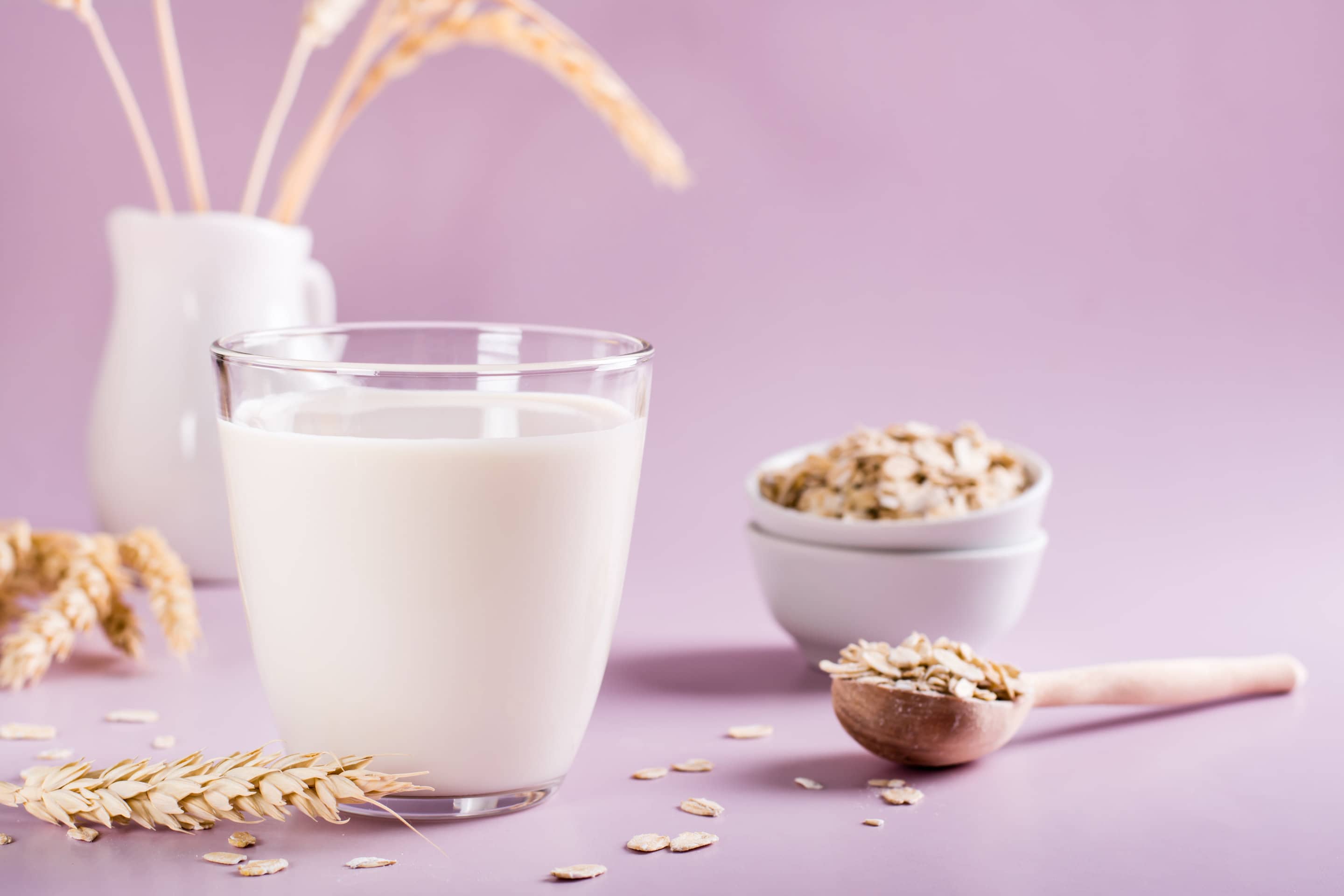 Homemade oat milk in a glass and oatmeal on the table